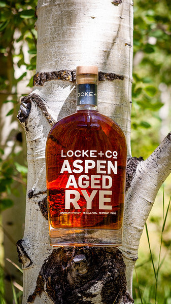 A Locke + Co. Aspen Aged Rye Whiskey Bottle in an Aspen tree