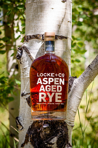 A Locke + Co. Aspen Aged Rye Whiskey Bottle in an Aspen tree