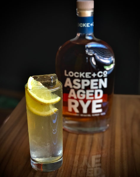 Summer Cocktail and a bottle of Locke + Co. Aspen Aged Rye Whiskey on a wood table