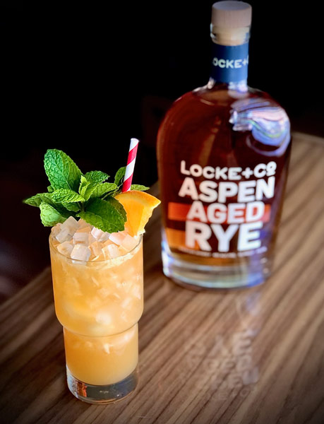 the locke cocktail and a bottle of Locke + Co. Aspen Aged on a wood table