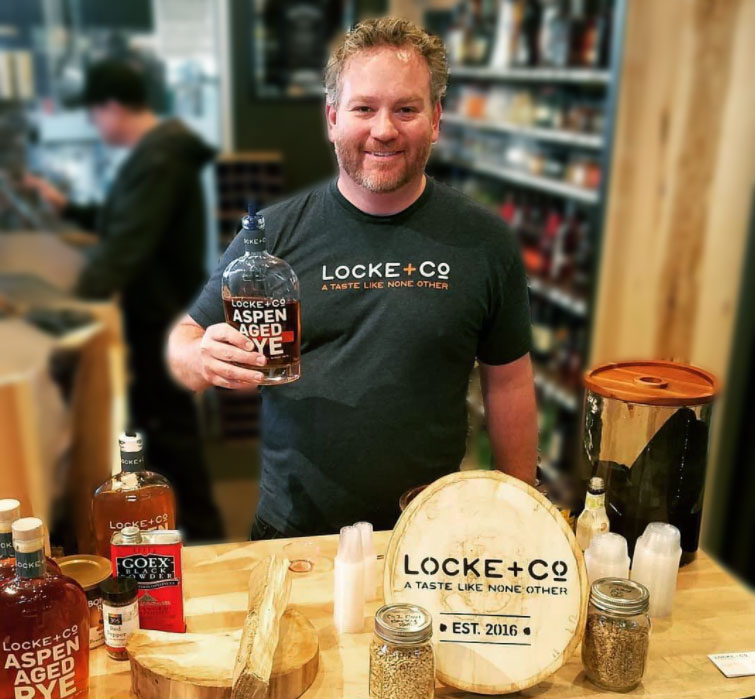 Owen Locke holding a bottle of Locke + Co. Aspen Aged Rye Whiskey at Rino liquors