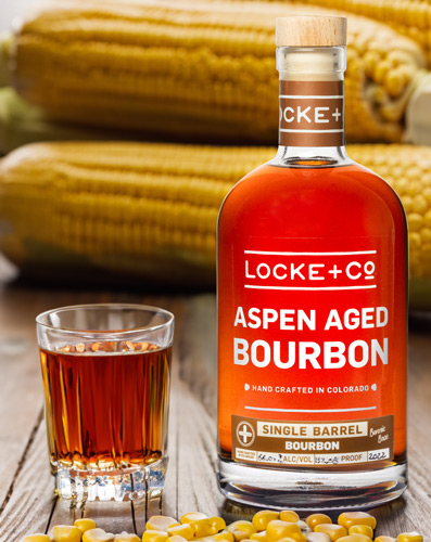 Locke Co. Distilling Bourbon next to glass with bourbon on a table with corn