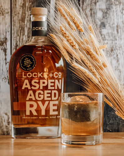 Locke Co. Distilling Rye next to glass with rye whiskey on a table with rye